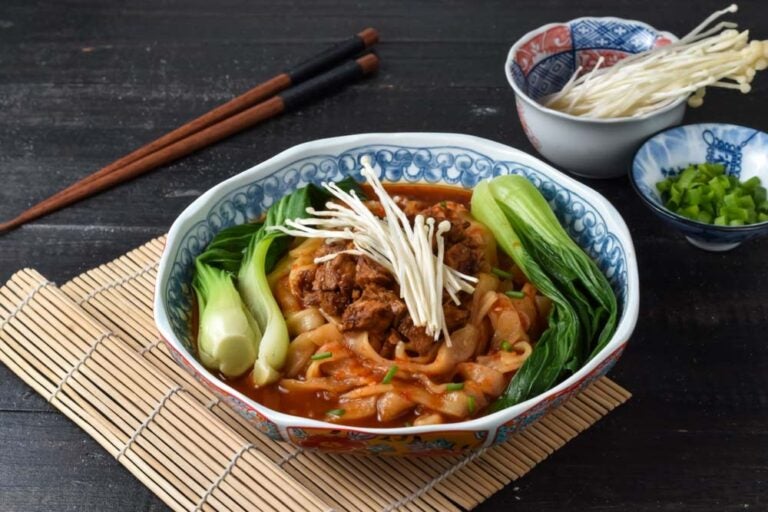 西安名物のビャンビャン麺に青菜と牛肉をのせたスパイシーな麺料理