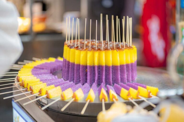 西安の屋台で販売される紫と黄色の米菓子の串スイーツ