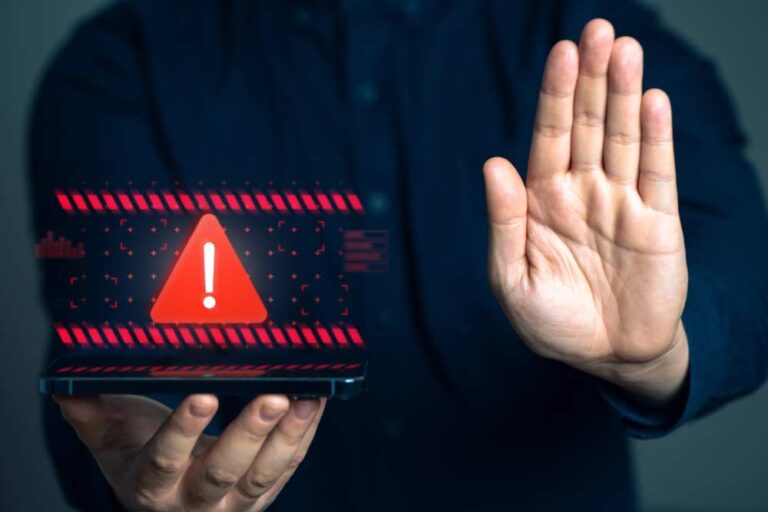 スマートフォンに表示された警告マークと「停止」を示す手のジェスチャー