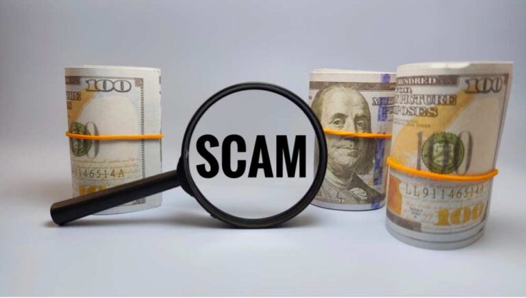 「SCAM」と表示された虫眼鏡と束ねられた紙幣のイメージ