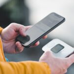 スマートフォンとモバイルWi-Fiルーターを手に持つ旅行者