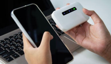 イモトのWiFiのようなモバイルルーターとスマートフォンを手に持つ人物のイメージ