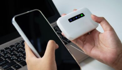 イモトのWiFiのようなモバイルルーターとスマートフォンを手に持つ人物のイメージ