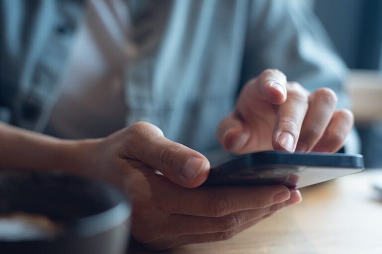 カフェでイモトのWiFiの料金プランをスマートフォンで確認するイメージ