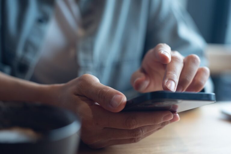 カフェでイモトのWiFiの料金プランをスマートフォンで確認するイメージ