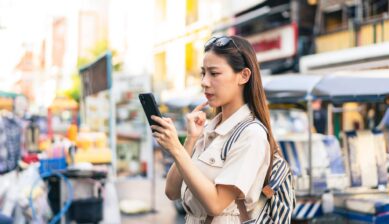 街中でスマートフォンのエラー画面を困った表情で確認する女性のイメージ