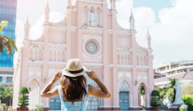 東南アジア・ベトナムのピンク色の大聖堂前に立つ女性旅行者のイメージ