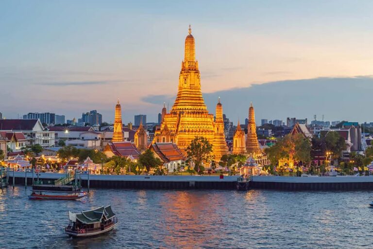 チャオプラヤー川越しに夕暮れのワット・アルンが輝くバンコクの夜景イメージ