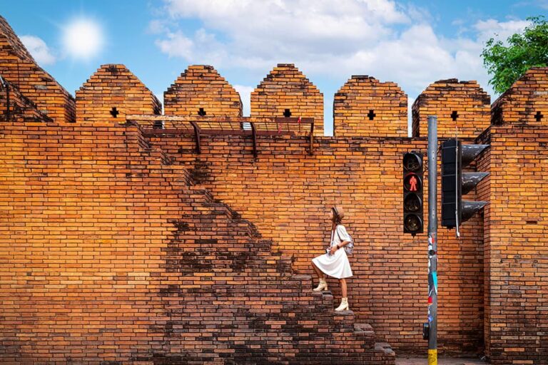 チェンマイ旧市街の赤レンガ城壁の前に立つ女性旅行者