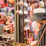 タイの雑貨市場で帽子をかぶった女性旅行者がお土産の小物を選んでいる様子
