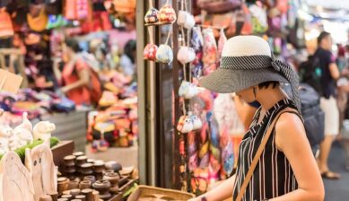 タイの雑貨市場で帽子をかぶった女性旅行者がお土産の小物を選んでいる様子