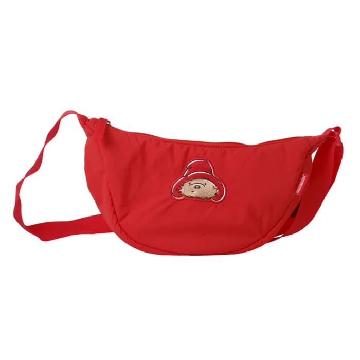 パディントン駅の公式ショップなどで手に入る、パディントン・ベアの顔が刺繍された赤い三日月型のクロスボディバッグ。雨の多いロンドンでも安心な耐水性素材で、旅先での身の回り品をまとめるのに最適な公式グッズ。