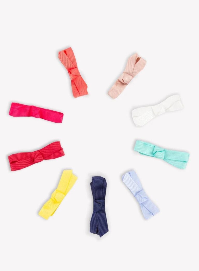 イギリスの老舗子供服ブランド「Trotters(トロッターズ)」のカラフルなヘアリボンクリップ。赤、ピンク、青、黄色など色とりどりのリボンが円状に並んだ、コンパクトで華やかなお土産のイメージ。