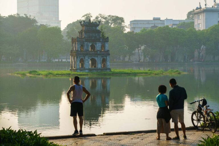 早朝のホアンキエム湖と亀の塔を眺める地元の人々