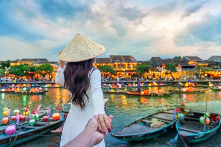 ノンラーをかぶった女性とランタンが灯るホイアン旧市街の川沿い