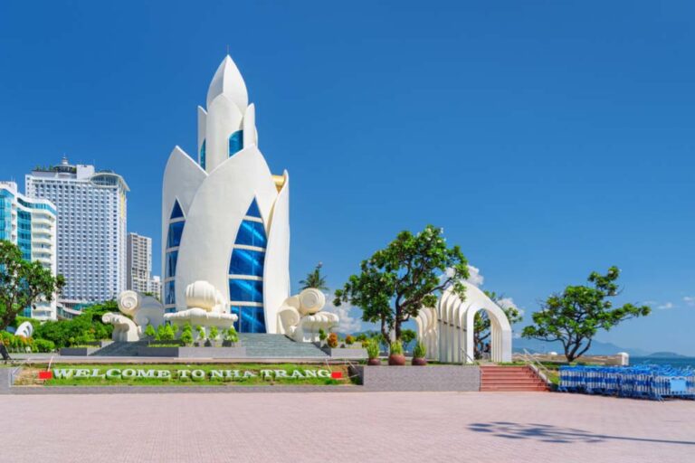 青空の下に建つニャチャンのウェルカムモニュメントと海沿いのホテル群