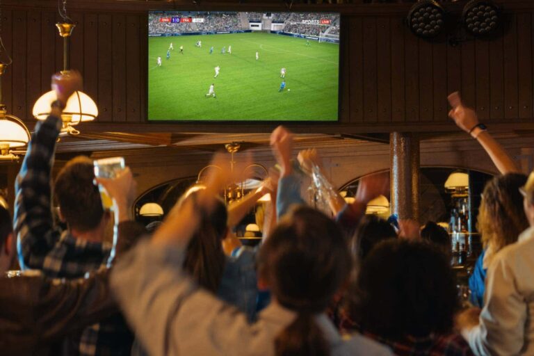 バーでサッカーワールドカップ2026の日本代表戦をテレビ観戦する盛り上がるサポーターのイメージ