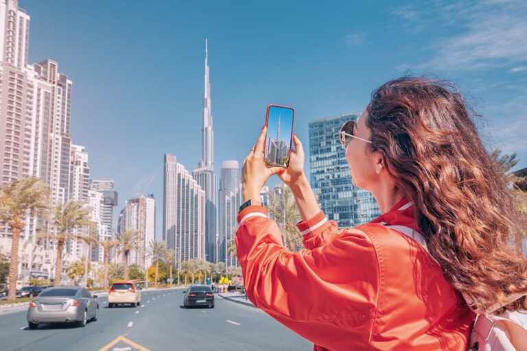 ドバイのダウンタウンでブルジュ・ハリファをスマートフォンで撮影する女性旅行者