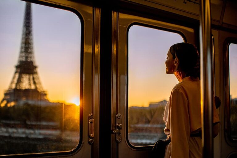 パリのメトロ車内から夕暮れのエッフェル塔を眺める女性