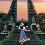 夕焼けのバリ島寺院の割れ門を訪れる旅行者