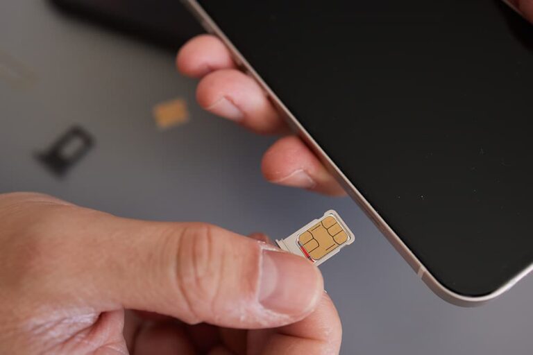 iPhoneのSIMトレイに新しいnanoSIMカードをセットしている手元のクローズアップ