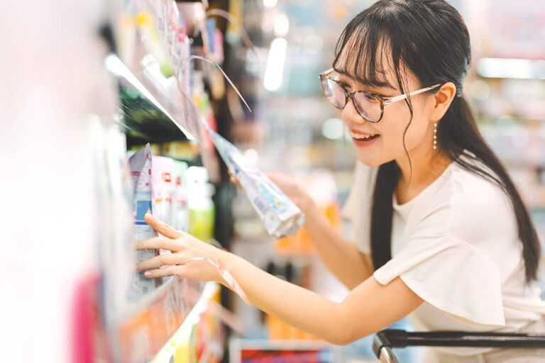 マレーシアのお土産探しに便利なスーパーマーケットで、棚の商品を手に取りながら笑顔で買い物をする女性の様子