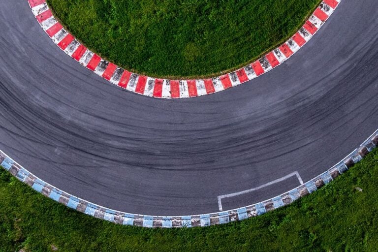 赤と青のカーブサイドが印象的なF1サーキットのヘアピンカーブを真上から捉えた俯瞰ショット