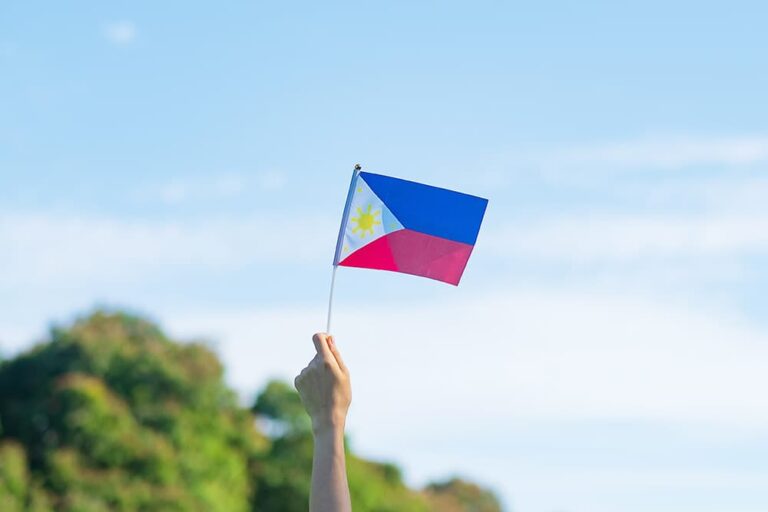 青空のもとフィリピン国旗を掲げる手