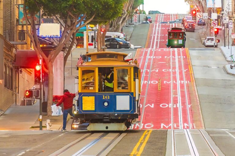 サンフランシスコの通りを走るケーブルカーと乗客