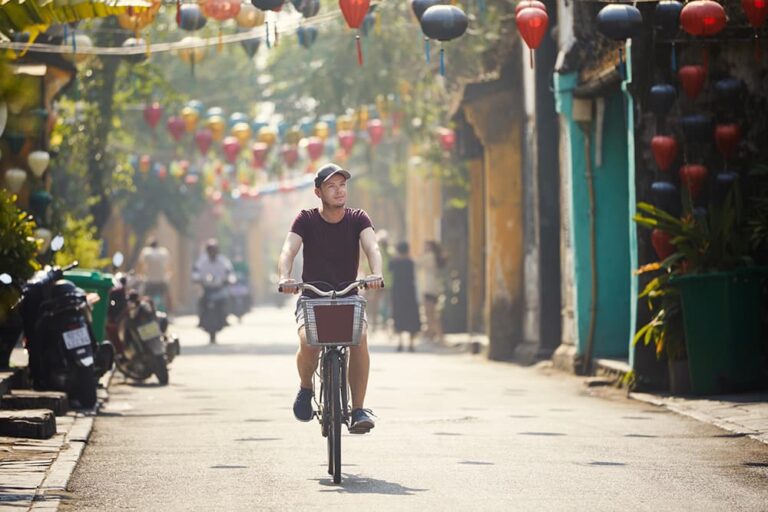 ランタンが飾られたホイアン旧市街を自転車で走る旅行者