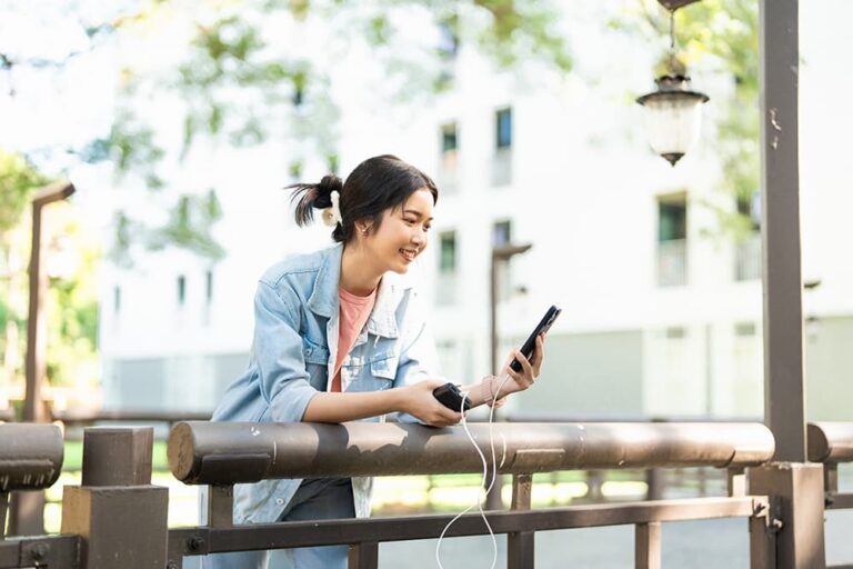 モバイルバッテリーでスマホを充電しながら屋外で使用する旅行者