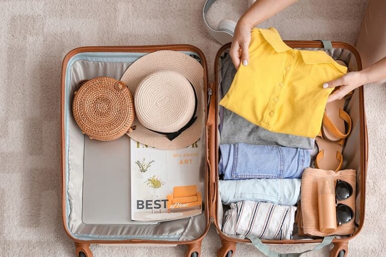 ハワイ旅行の準備中に服や帽子をスーツケースに詰める様子