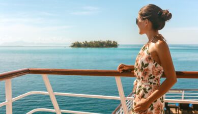 クルーズ船のデッキからハワイの青い海と島を眺める女性