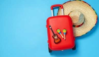 赤いスーツケースとソンブレロ、マラカスが並ぶメキシコ旅行のイメージ