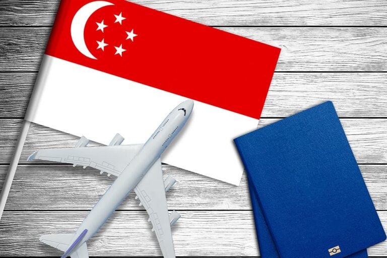 シンガポール国旗の上に置かれた飛行機の模型とパスポート