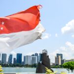 青空のもとマリーナベイのスカイラインを背景にはためくシンガポール国旗