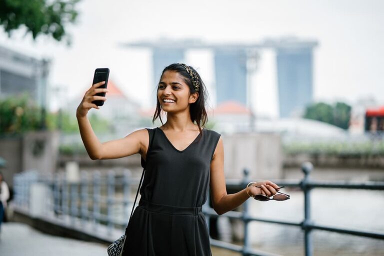 曇り空のシンガポールでスマホ自撮りを楽しむ女性旅行者