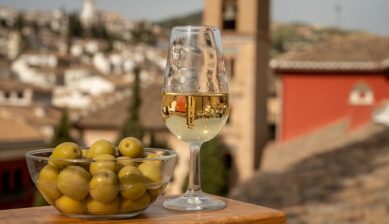 スペインの街並みを背景にオリーブとワインが並ぶテーブル