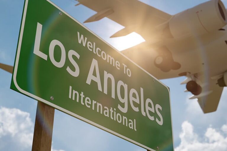 上空を飛ぶ飛行機とロサンゼルス国際空港（LAX）の案内標識。帰国直前にお土産を購入できる空港の入口イメージ