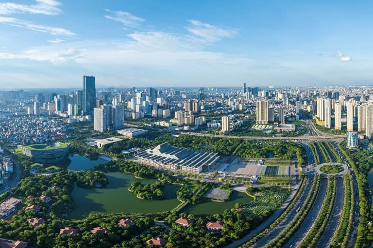 青空のもと緑豊かな公園と近代的なビル群が広がるハノイの街並みを空から捉えた一枚