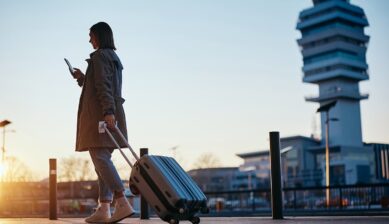 空港でスーツケースを引きながらスマートフォンのGoogleマップを確認する旅行者の様子