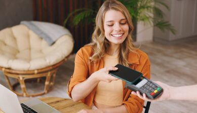 海外の店舗でスマートフォンのApple Payを使い、笑顔で非接触決済を行う女性