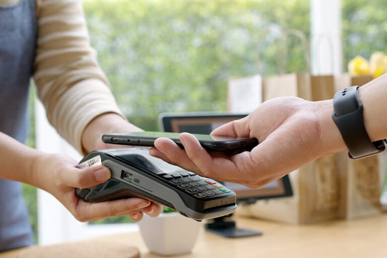 店舗の決済端末にスマートフォンをかざしてApple Payで支払う様子