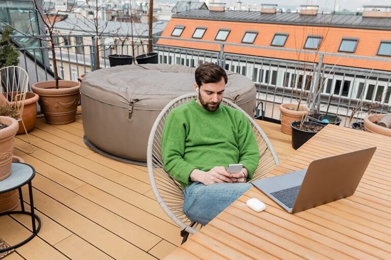 オーストリアの屋上テラスでスマホとノートPCを使う旅行者