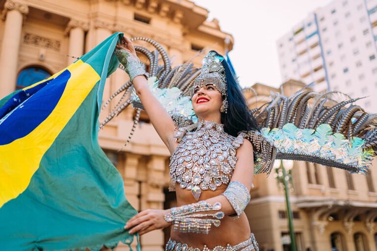 ブラジル国旗を掲げ羽根飾りの衣装で舞うリオのカーニバルのサンバダンサー