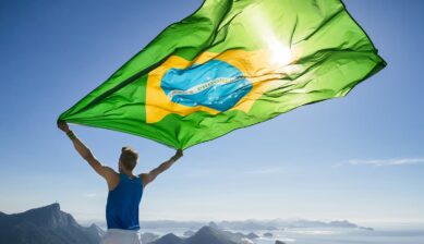 コルコバードのキリスト像を望むリオデジャネイロの絶景を背景にブラジル国旗を掲げる人物