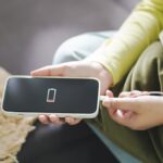 バッテリー残量が少なくなったスマートフォンに充電ケーブルを差し込む様子。中国旅行中の充電準備の重要性を示す一枚