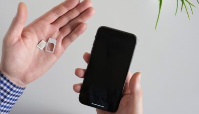 物理SIMカードとスマートフォンを両手に持ち、SIMの種類を見比べる様子