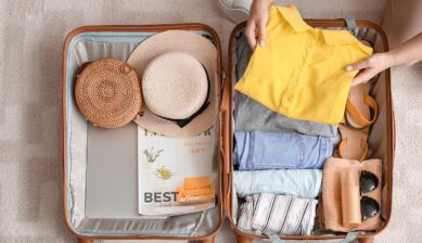 グアム旅行の持ち物を衣類や帽子とともにスーツケースへ整理して詰める様子