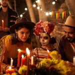 死者の日の夜に祭壇のろうそくを灯すメキシコの家族とフェイスペイントをした子ども